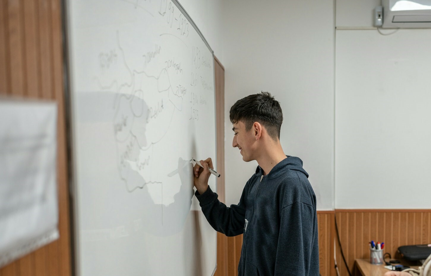 Student writing on whiteboard during study session