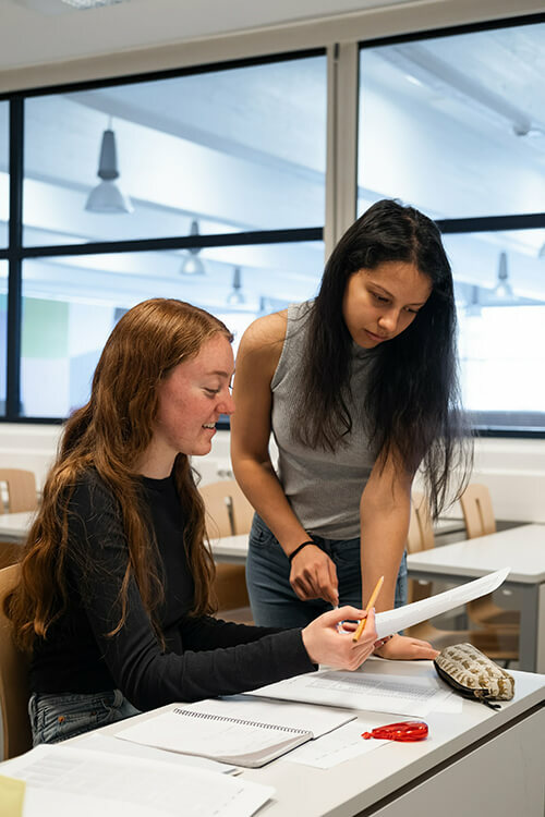 Female student in class discussing work with trainer