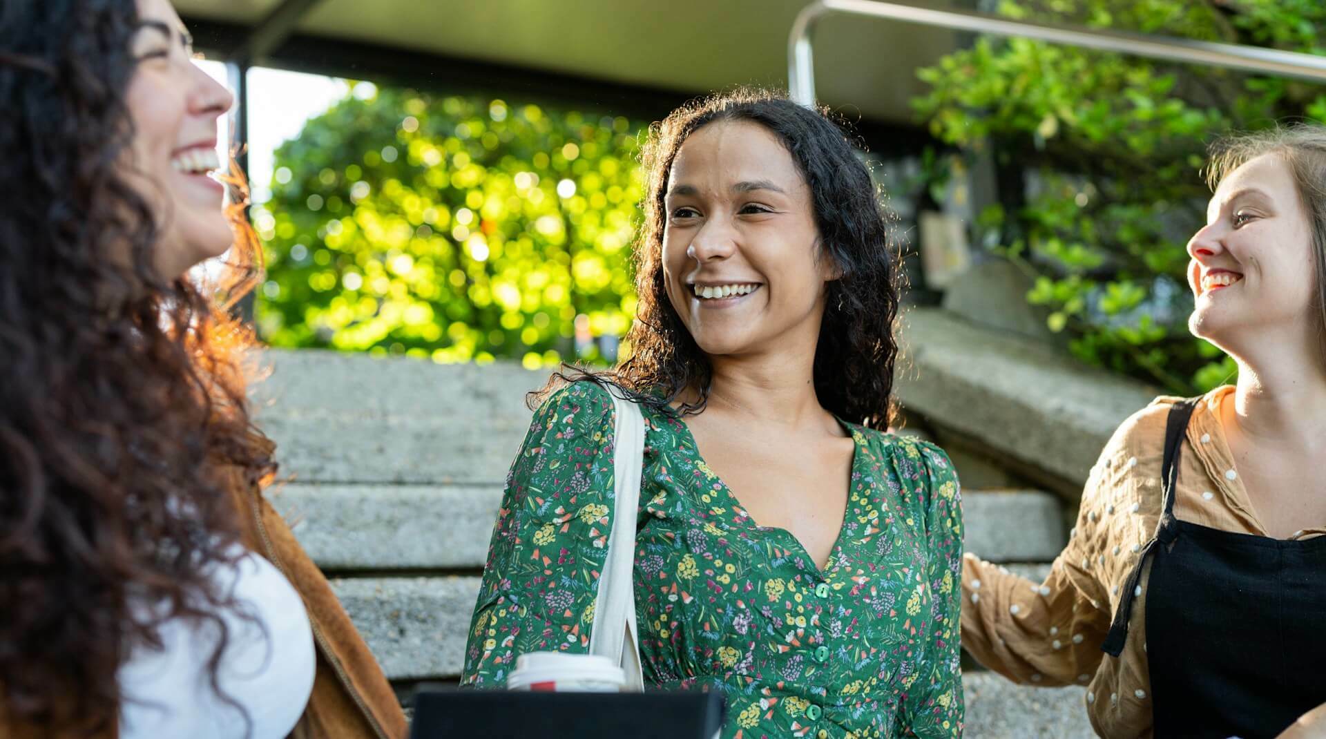 Three students sitting on steps laughing