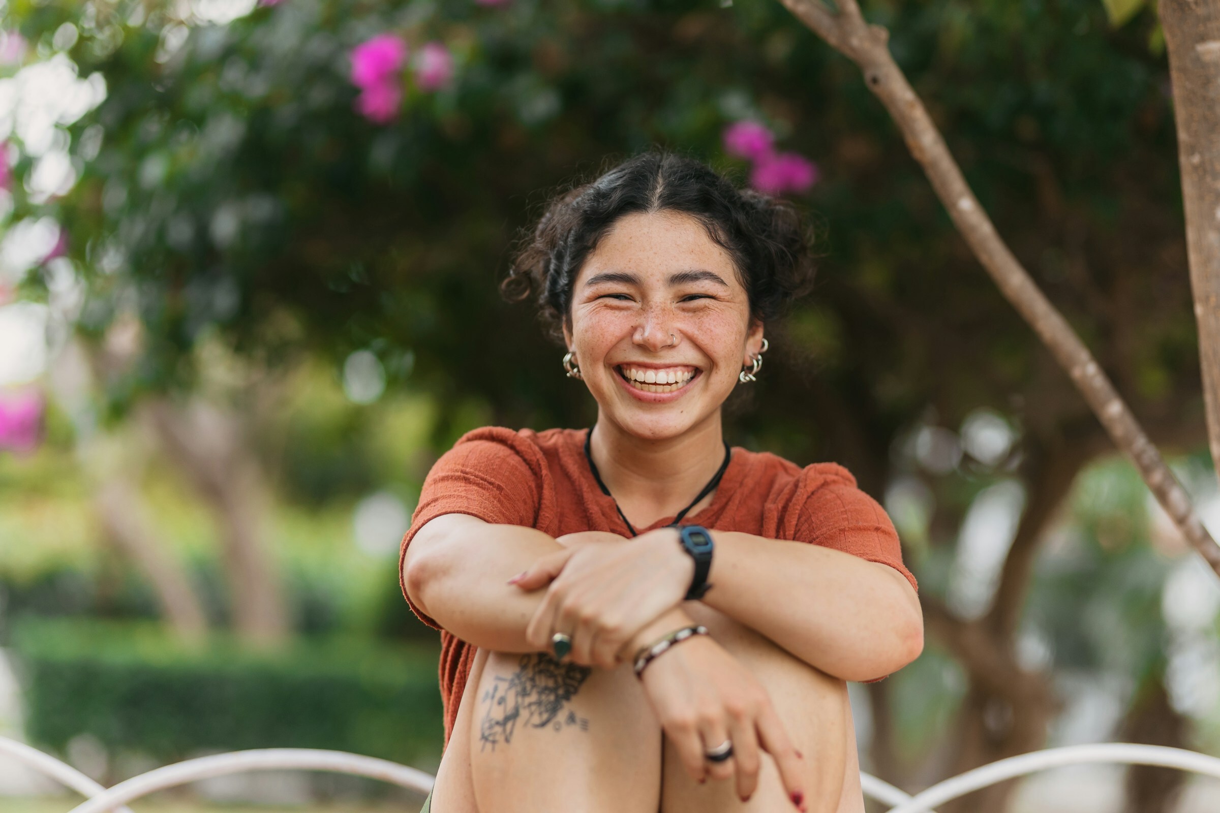 Young woman smiling while sitting outdoors in a garden setting